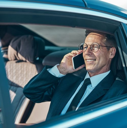 Cheerful businessman talking on smartphone during transfer from airport